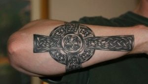 Tatuaj bărbătesc sub formă de cruce pe braț